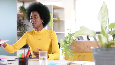 mujer de negocios afroamericana con afro usando documento en la oficina, en cámara lenta