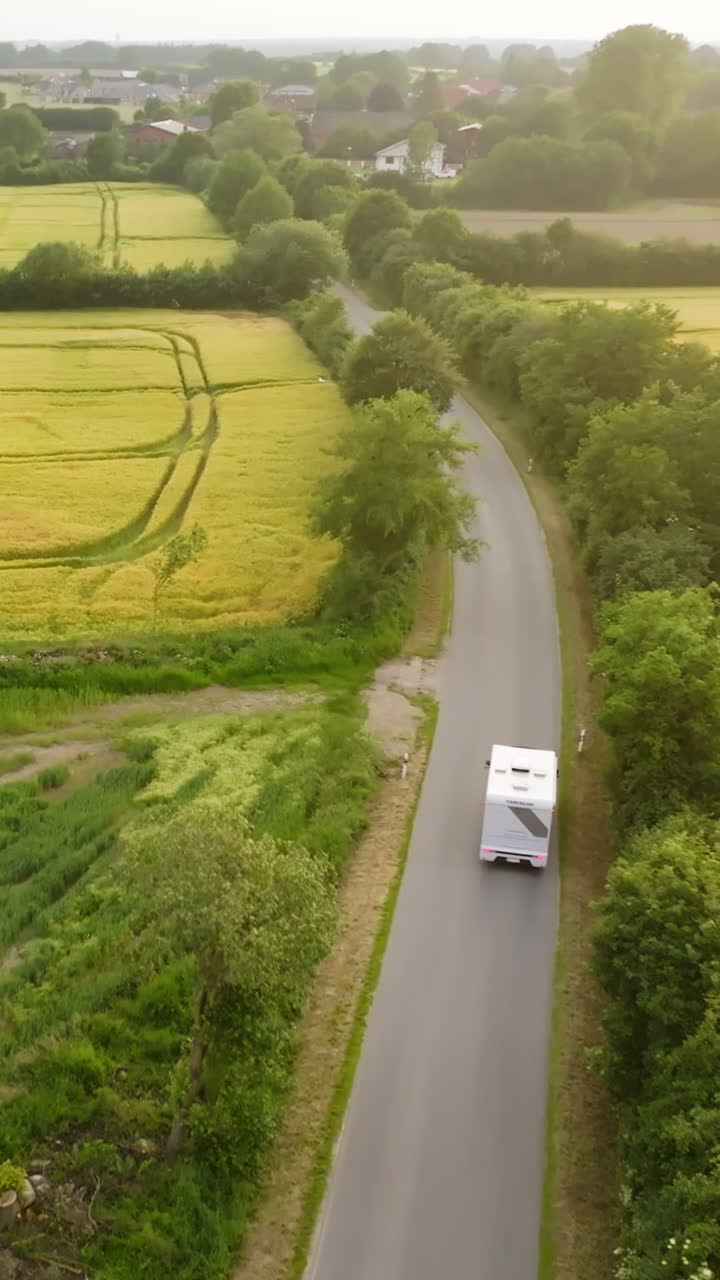 Drone flying after a Camper van driving on a countryside road, sunny evening
