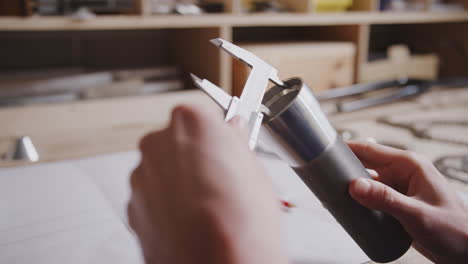 close up of engineer in workshop measuring components for bicycle with micrometer