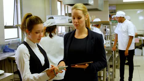 female manager and female chefs discussing over clipboard 4k