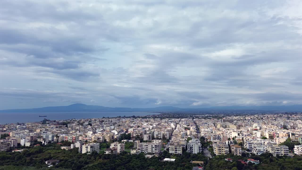 Aerial high angle, parallax orbital footage , Kalamata cityscape with a view to Messinian gulf on a cloudy autumn day 4K