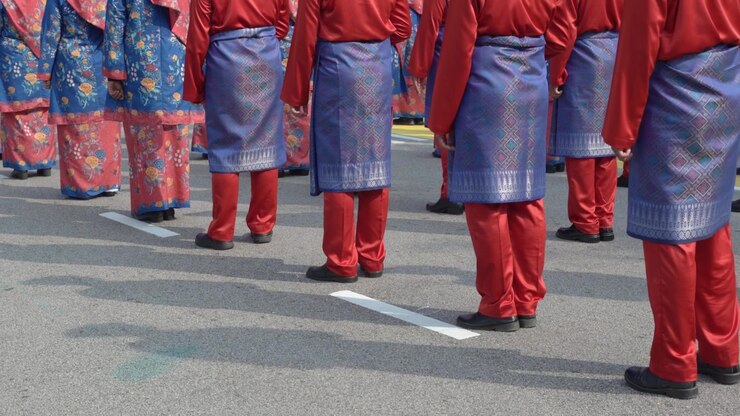 Group of participants wearing red traditional Malay attire stand in formation during an outdoor cultural parade in Malaysia