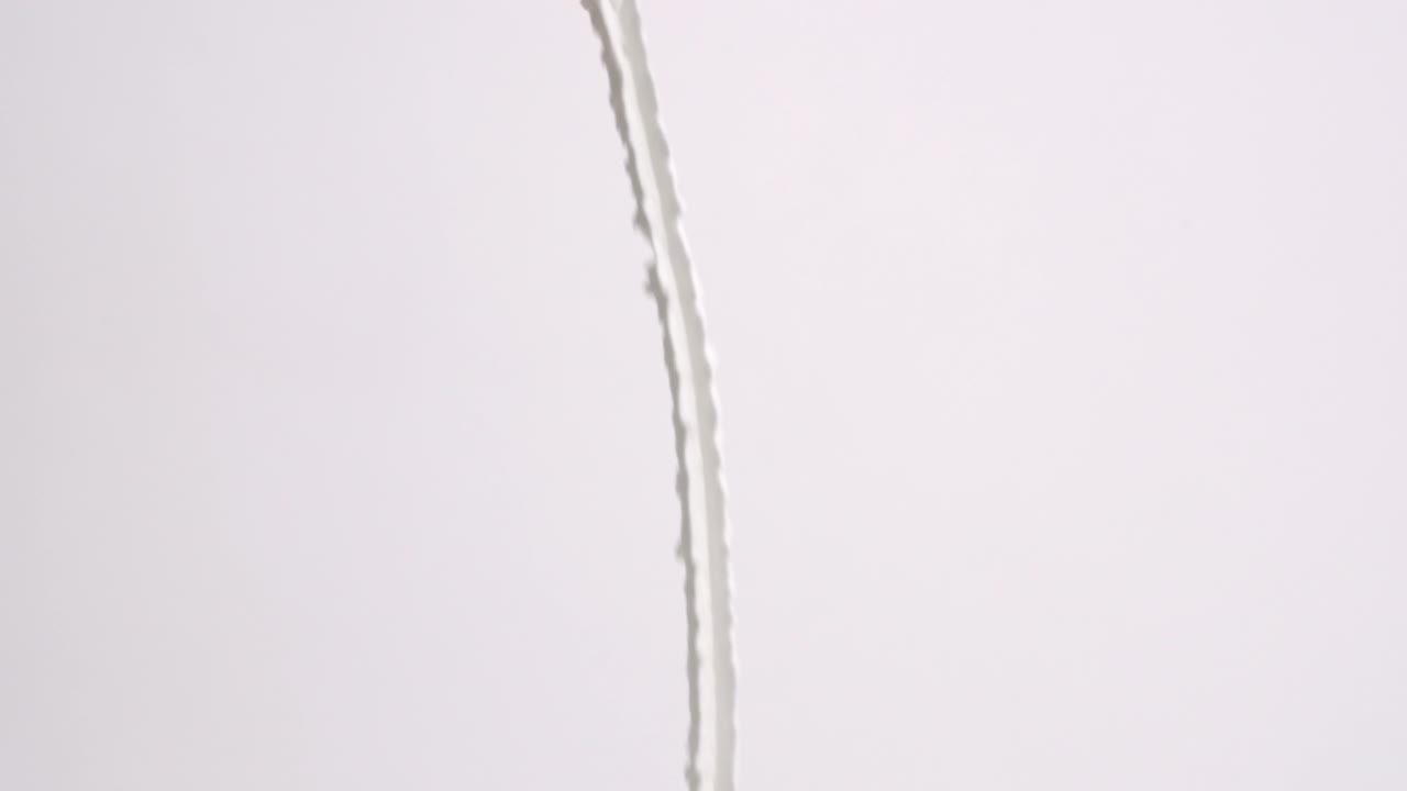 슬로우 모션으로 흰색 배경에 비가 내리는 흰색 푹신한 휘핑 크림 리본