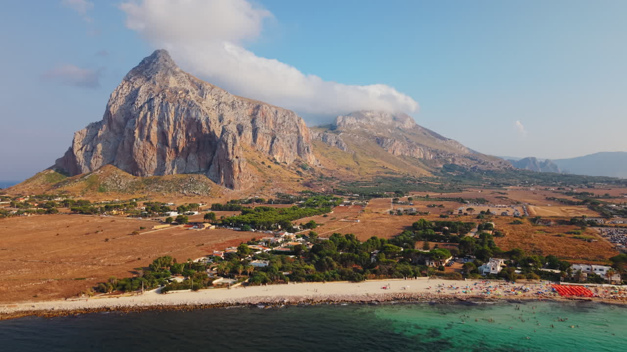 Aerial shot moving forward and rising above beach towards mountain and clouds in San Vito Lo Capo