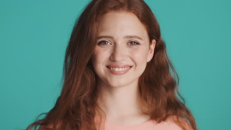 Redheaded-girl-in-front-of-camera-on-turquoise-background.