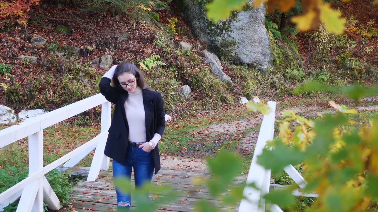 가을날 슬로우 모션으로 공공 공원에서 다리 위를 걷는 캐주얼한 10대 소녀