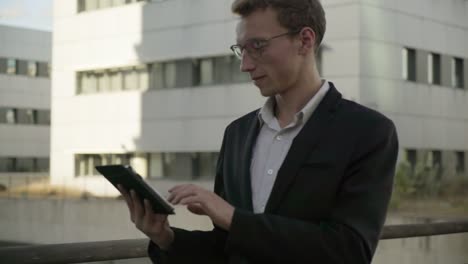 Good looking man walking outside, working on tablet