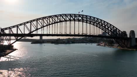 cinematic aerial view flying under sydney harbour bridge at sunset, sydney landmark, australia