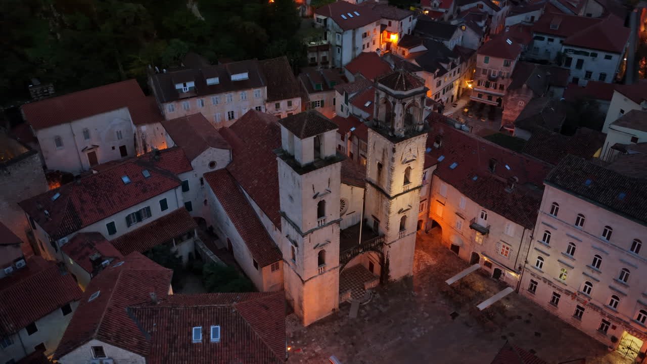 Luftfoto af Sankt Tryphons katedral omgivet af middelalderlige stenbygninger i tusmørket, der viser den historiske arkitektur i varm belysning. Kotor, Montenegro