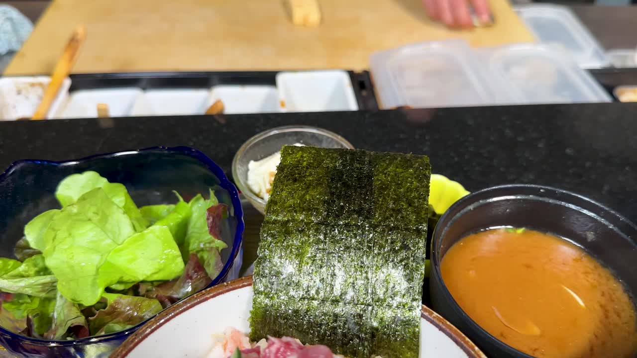 Um chef profissional coloca uma tigela de frutos do mar kaisen don fresca no balcão de um restaurante