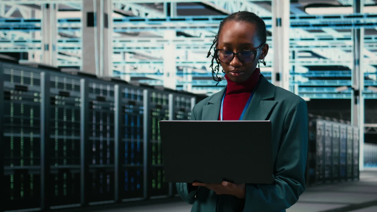 Young African American Woman Using Laptop in Server Room