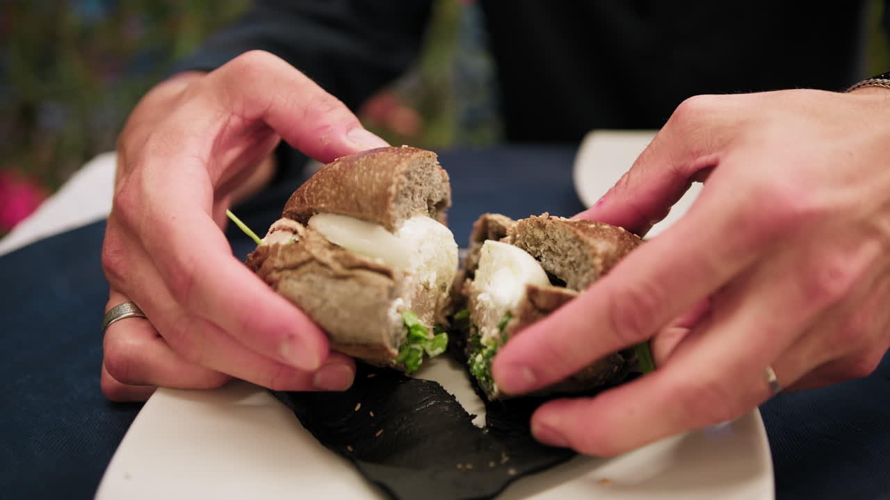 Man Dividing A Burger In Half With The Hands During Dinner At The Beach Resort