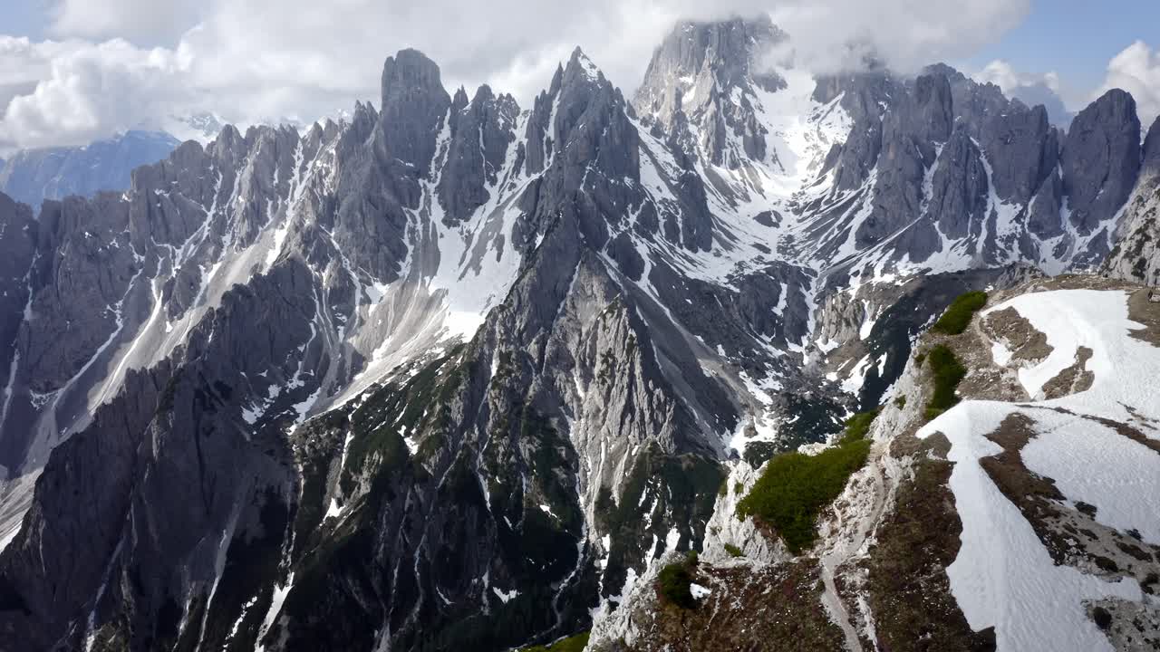 una aguda cordillera rocosa que se eleva por encima de un increíble valle verde con nieve