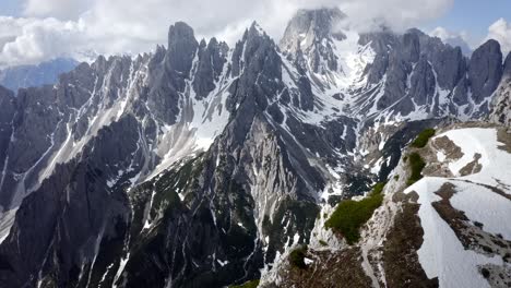 Ein-Scharfer-Felsiger-Bergrücken,-Der-Sich-über-Einem-Erstaunlich-Grünen-Tal-Mit-Schnee-Erhebt