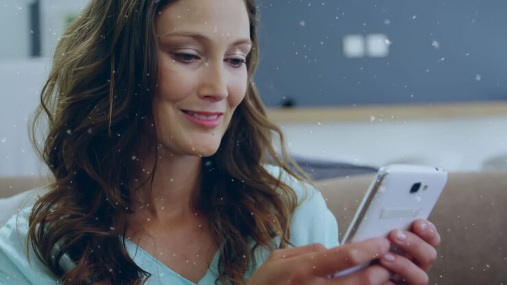 Animazione di neve che cade su una donna caucasica felice che usa lo smartphone