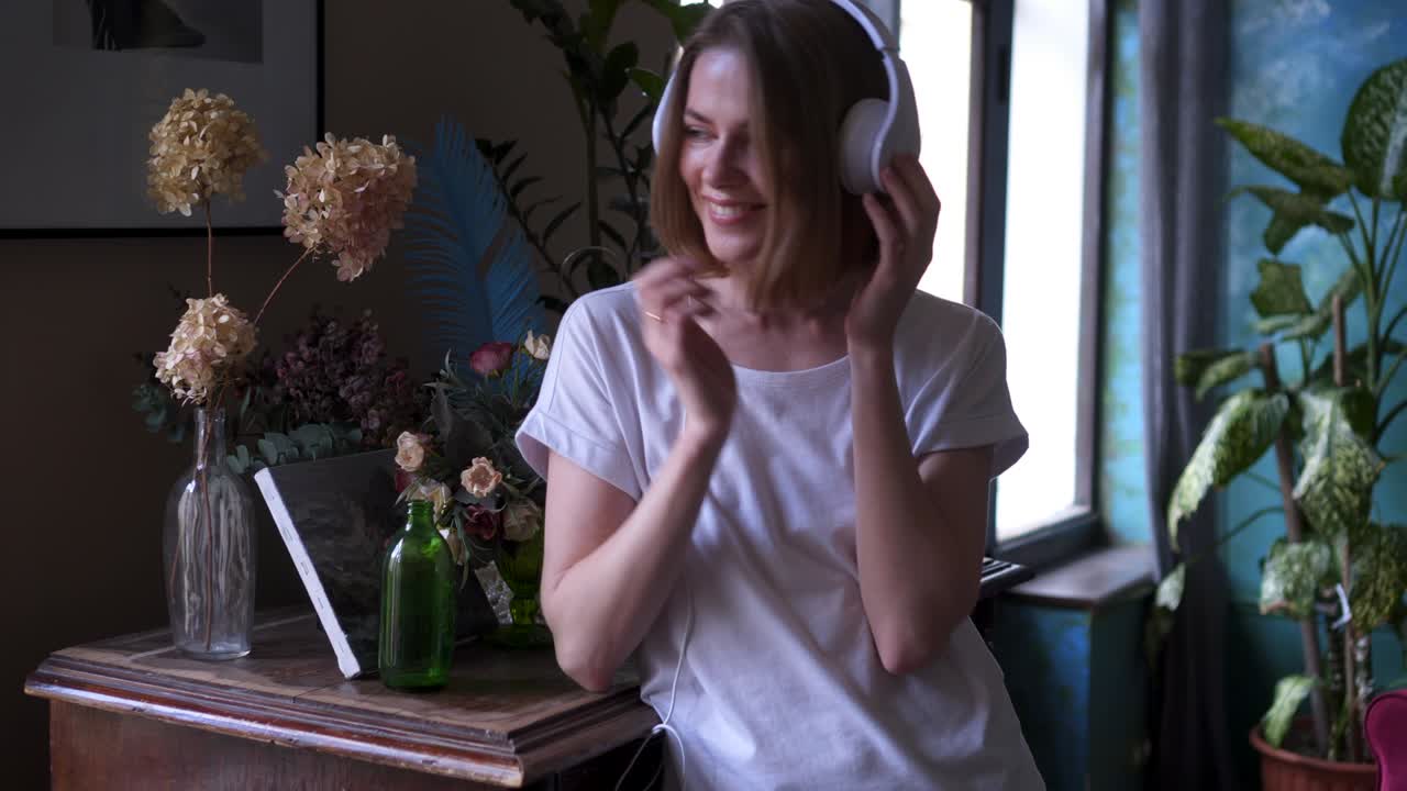 una mujer joven con un traje casual disfrutando de la música en casa.