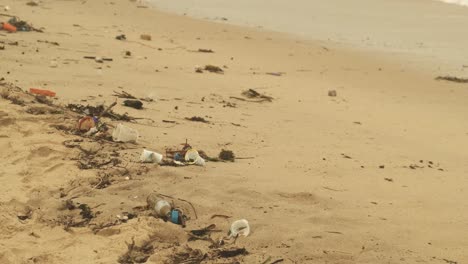 plastic cup and bottle trash polluting sandy beach in malaysia in the day