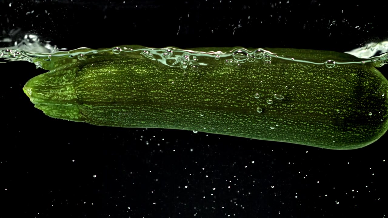 Zucchine verdi fresche immerse nell'acqua con bolle