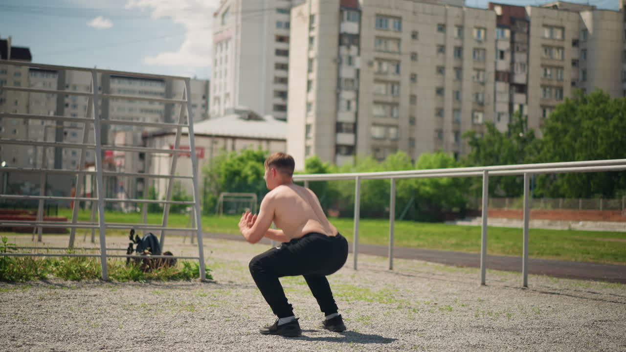 Practicar ejercicios para la parte inferior del cuerpo al aire libre, realizar entrenamiento de fuerza en el exterior para las piernas y la parte inferior del cuerpo, hombre realizando rutinas de sentadillas al aire libre centradas en mejorar la fuerza de las piernas y la parte inferior del cuerpo