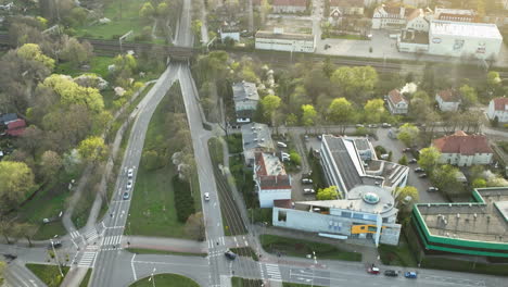 Die-Abenddämmerung-Wirft-Einen-Sanften-Schein-über-Eine-Städtische-Kreuzung-Mit-Geschäftigem-Verkehr,-Die-Einen-Kreisverkehr-Mit-Einer-Gepflegten-Mittelinsel-Umgibt,-Flankiert-Von-Wohn--Und-Geschäftshäusern