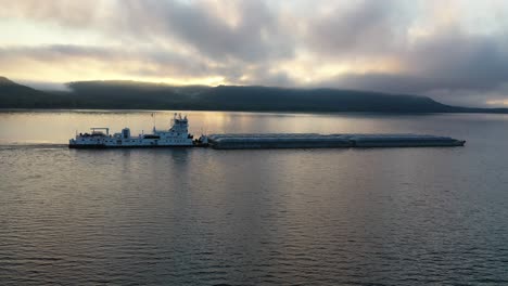 tugboat and barge on a river at sunrise/sunset