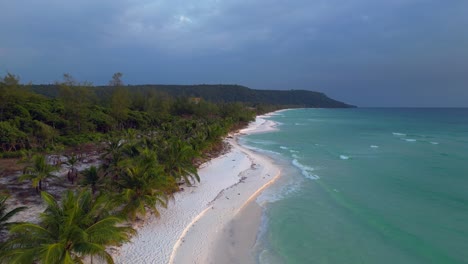 turquoise waves crashing on the white sandy sok san beach in koh rong island, cambodia, at sunset. overflight flyover fly push forward drone