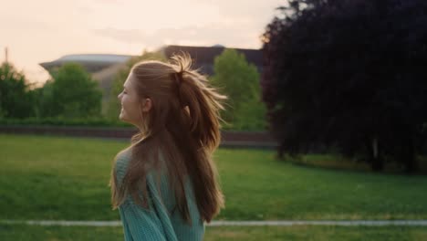 Caucasian-young-woman-walking-across-the-park-and-turning-towards-the-camera.