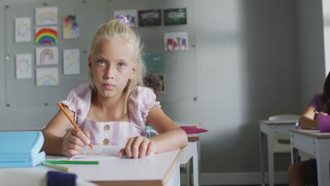 Video-of-focused-caucasian-girl-sitting-at-desk-in-classsroom