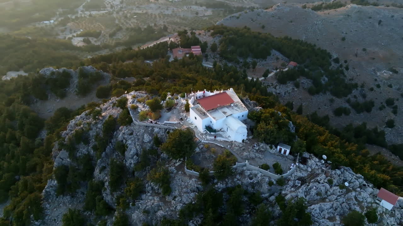 High angle drone shot orbiting the Tsambika Monastery, sunset in Rhodes, Greece