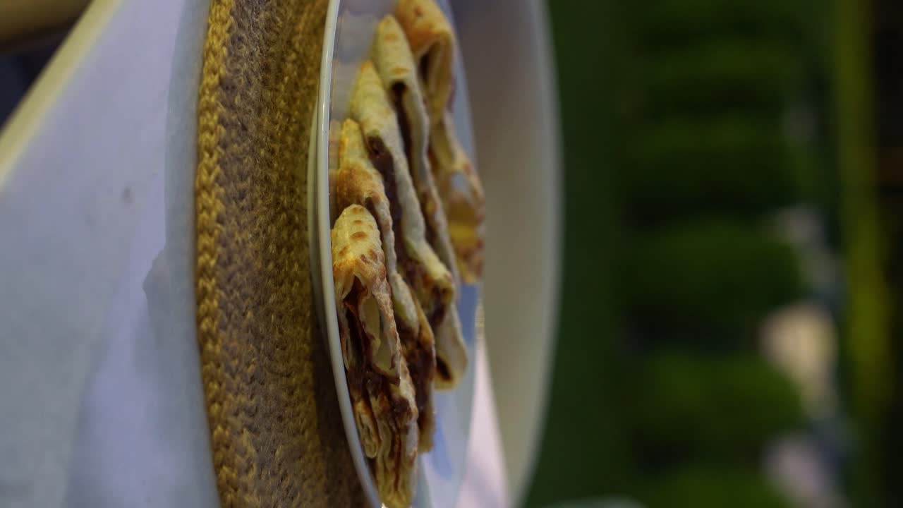 Uno chef aggiunge salsa al cioccolato su un piatto, primo piano, inserto, video verticale.