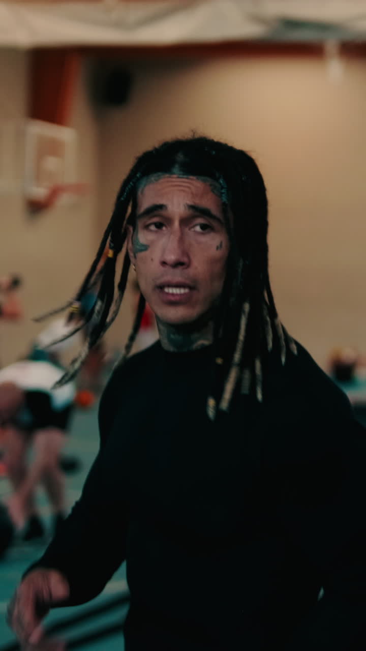 Uomo concentrato con dreadlock e tatuaggi che si allena in palestra