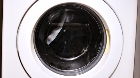 washing machine drum spins laundry at high speed through round glass window