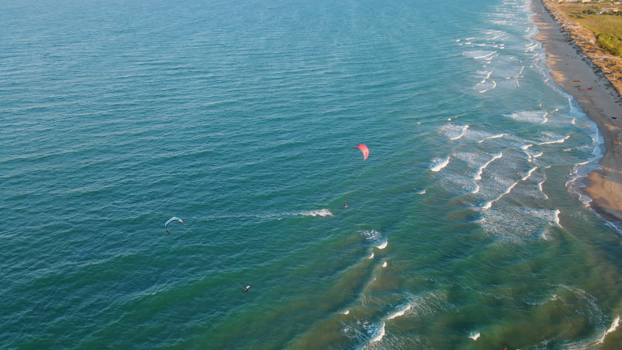 vista aérea de kitesurfer saltando sobre las olas durante la puesta de sol en la playa de mareny, valencia, españa