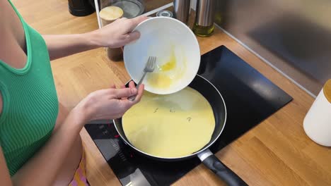 mujer cocinando huevos en una sartén