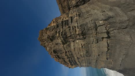 vertical fpv: flight up rugged rock strata sea stack, portugal coast