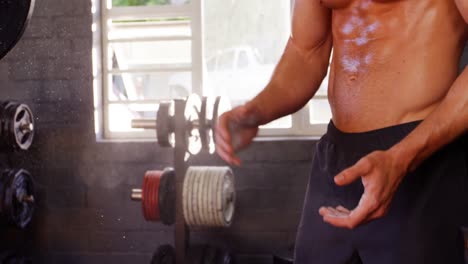 Mid-section-of-man-dusting-his-hands-with-chalk-powder