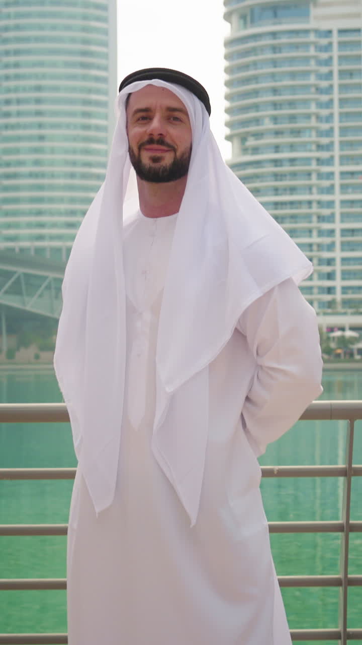 Ritratto verticale di un uomo arabo del Golfo in abiti tradizionali emiratini con torri e grattacieli sullo sfondo.