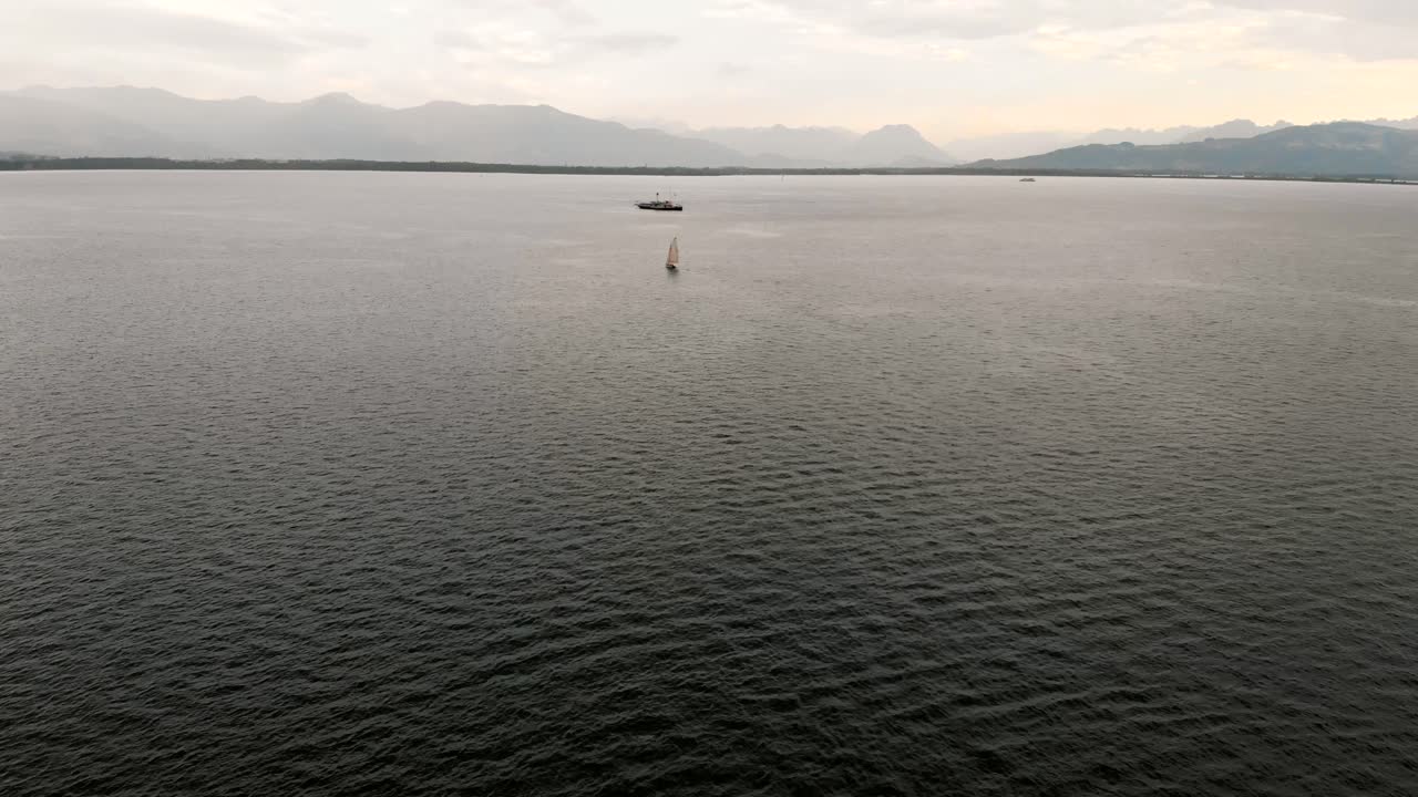 독일 린다우 해안의 콘스탄스 호수 위를 날아다니는 드론 뷰, 구름이 가득한 하늘과 비밀스러운 산을 배경으로 4k