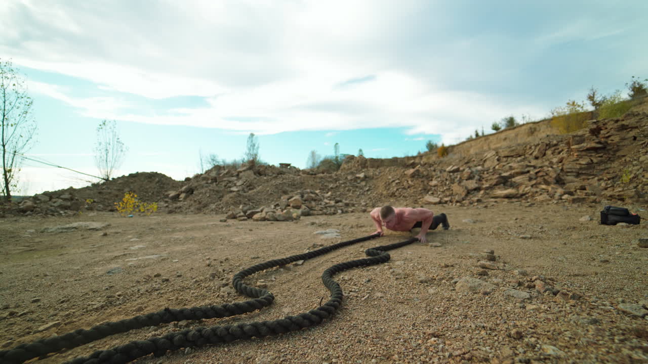 Athlete doing battle rope workout. Muscular young man working out with battling ropes