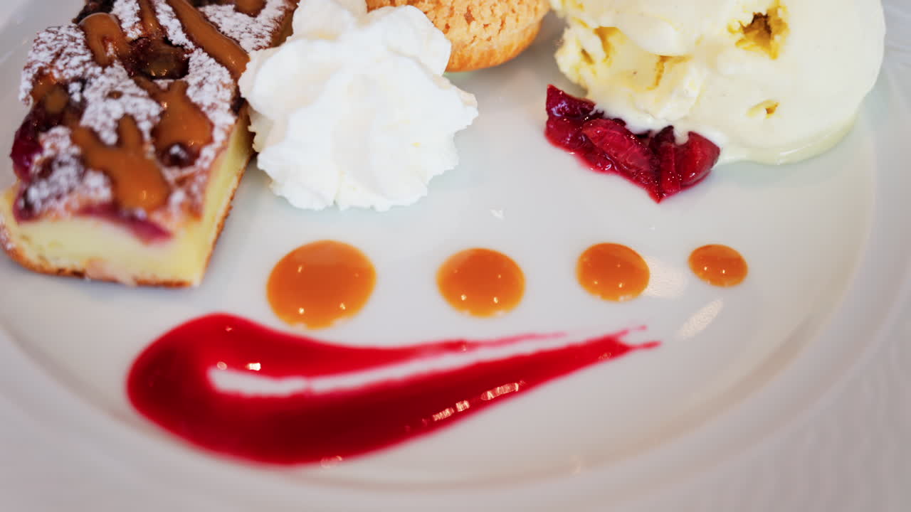 Close up of a dessert plate with a tart, a cream puff, ice cream, and sauces