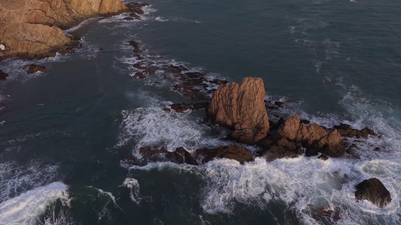 Maestosa vista aerea del Reef delle Sirene a Cabo de Gata, Spagna. Le onde dell'oceano si infrangono contro drammatiche formazioni rocciose vulcaniche al tramonto.