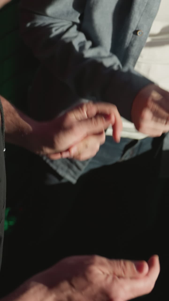 primer plano de dos hombres chasquando los dedos rítmicamente cerca de un soporte de micrófono en un estudio de grabación a prueba de sonido. caras no visibles, vestidos casualmente, uno con una camisa negra y el otro con una camiseta azul