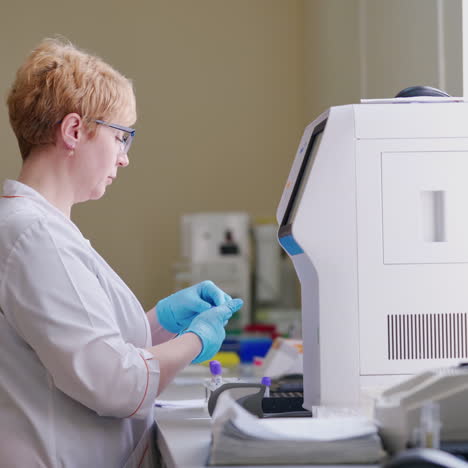 side view of a laboratory worker. modern equipment inside the microbiology cabinet. woman in medical uniform testing samples in a research laboratory.