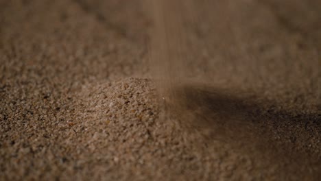 Close-up-reversed-shot,-gold-rings-being-uncovered-by-the-sand-particles-on-a-windy-sunny-day-at-the-beach