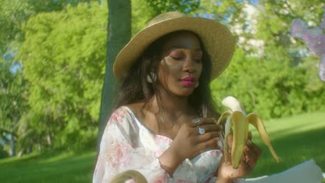 Black-Woman-calmly-peeling-banana-on-picnic-in-park-close-up