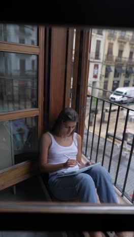 young woman working on a digital tablet on a balcony in a city