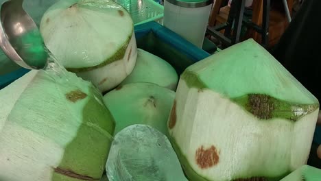 close-up view of green coconuts and ice in a blue container.