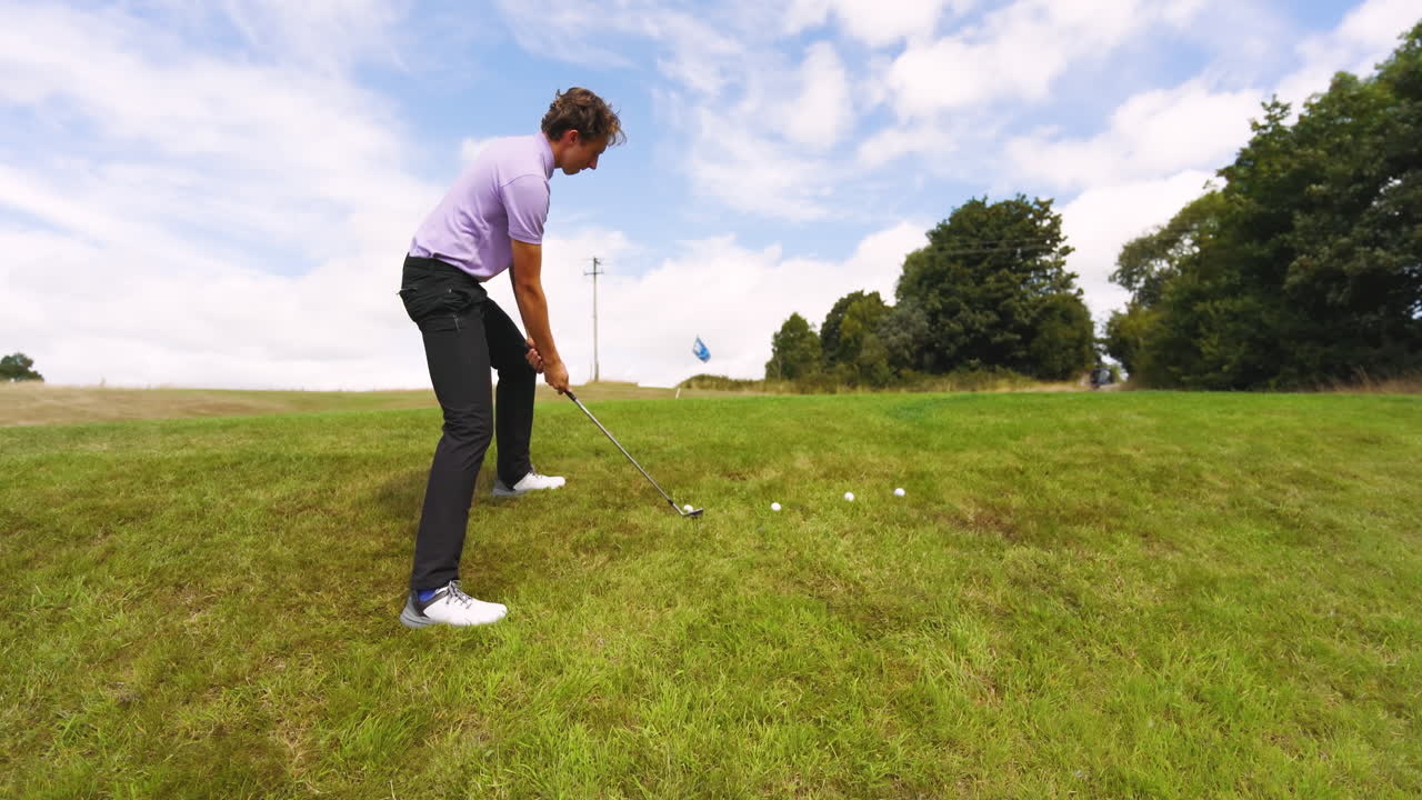 Male golf player wearing blue uniform, playing golf and knocking golf balls out on golf course