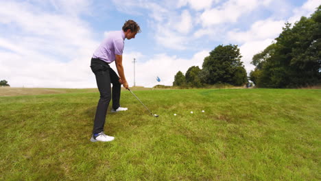 male golf player wearing blue uniform, playing golf and knocking golf balls out on golf course