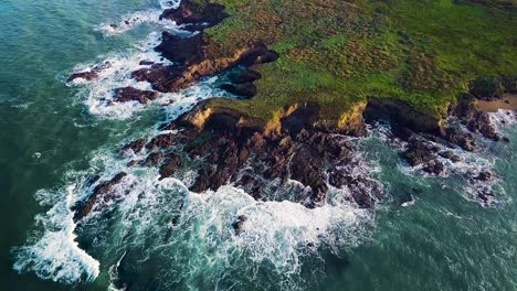 flying toward rocky california cliffs with waves breaking at sunrise